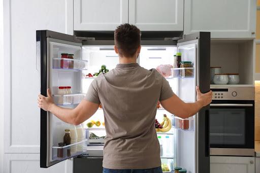 A man looking inside a fridge.